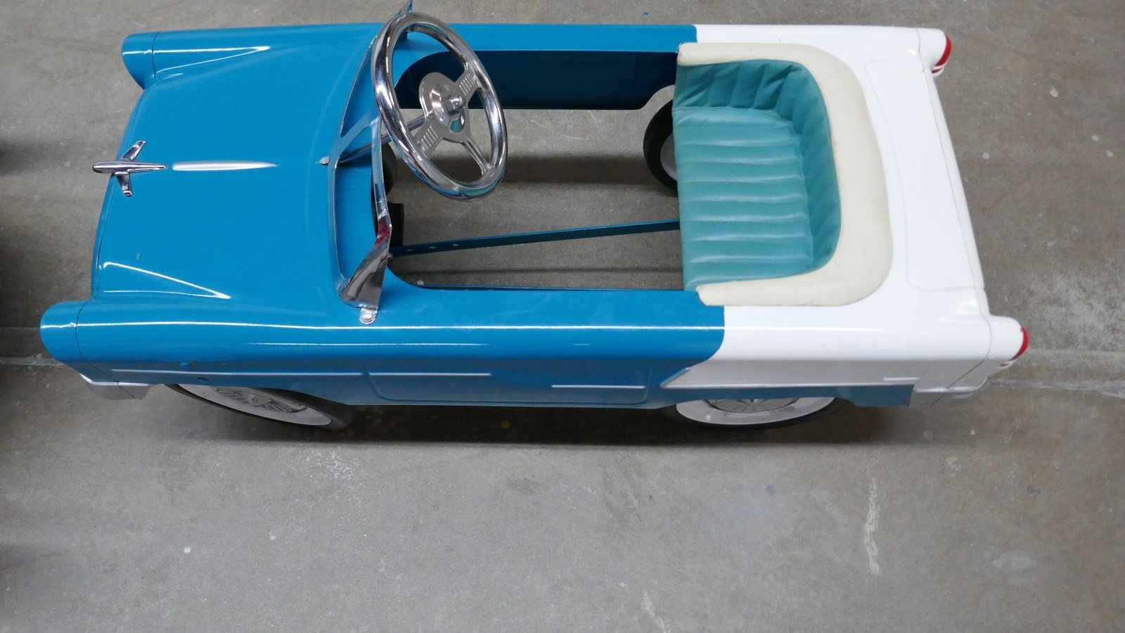 Ein blau-weißes Tretauto mit Lenkrad